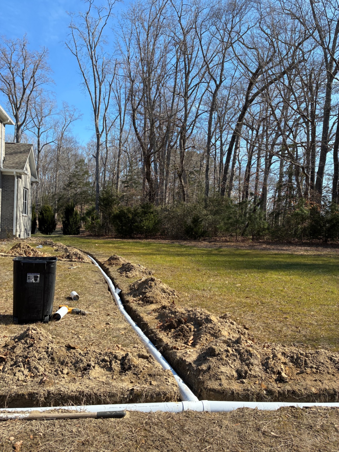 French drain trench installation running across a backyard in Hampton Roads